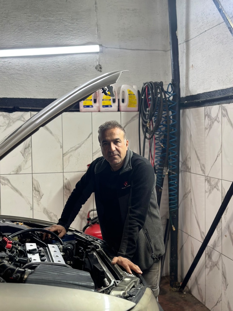 Tuncay Usta servisinde bir otomobilin motorunu incelerken